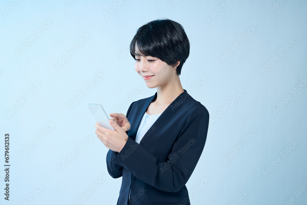 スマートフォンを操作するショートヘアの女性会社員 スマートフォンを操作するショートヘアの女性会社員