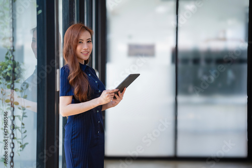 A beautiful Asian woman holding a digital tablet in an office room with copy space. Free Download A beautiful Asian woman holding a digital tablet in an office room with copy space. - GFXLoad