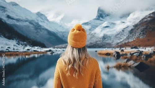 Portrait from the back of the girl traveler in an orange sweater and hat in the mountains against the background of a frozen mountain. Photo travel concept photo