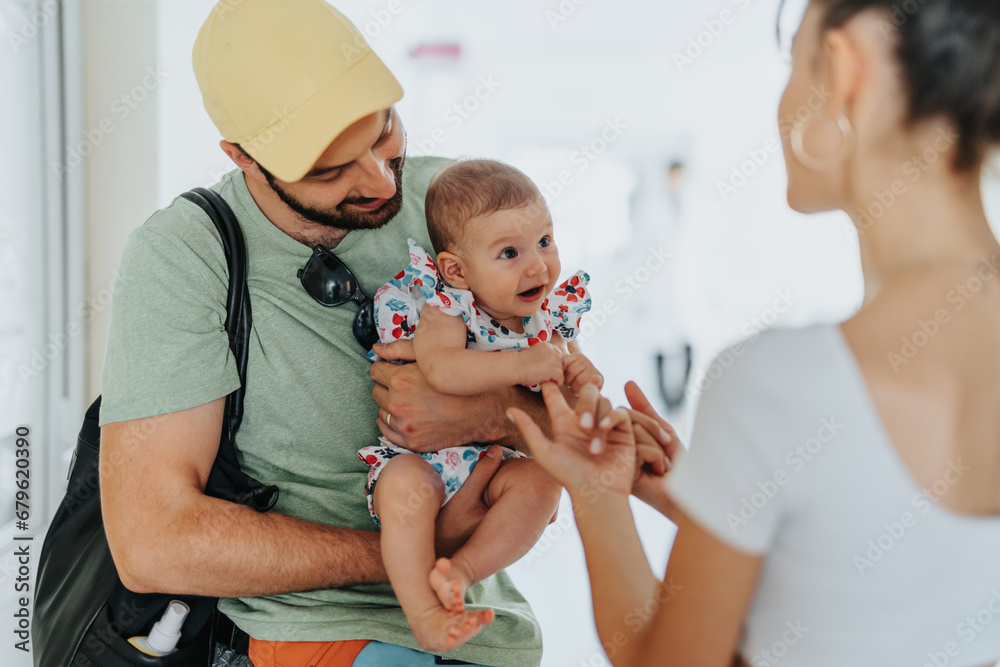Father holding baby girl. Mother playing with baby daughter while waiting for the doctors call for medical check ups. Father holding baby girl. Mother playing with baby daughter while waiting for the doctors call for medical check ups.