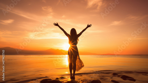 woman in beach shore at sunset raising arms photo