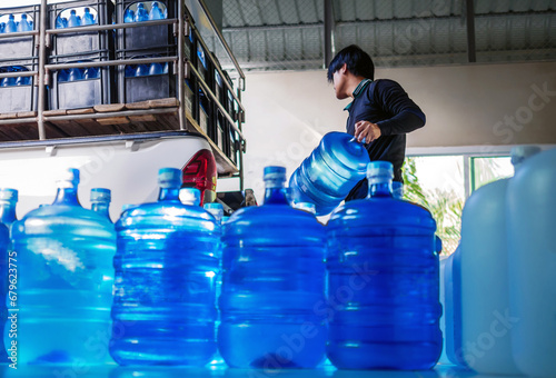 Workers lift drinking water .clear and clean in blue plastic gallon into the back of a transport truck purified drinking water inside the production line to prepare for sale. small business photo