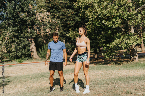 Young, fit couple exercising outdoors in a sunny park. Motivated and persistent, they practice fitness and stretching, embracing a healthy lifestyle.