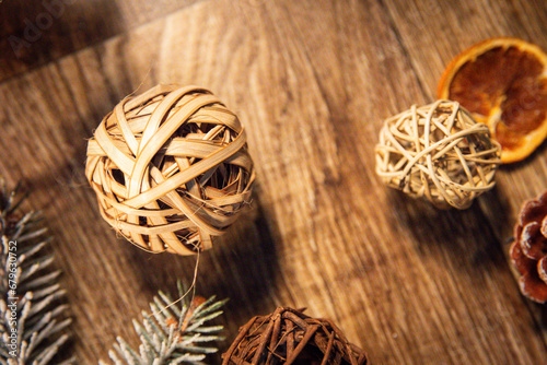 Balls on a wooden table among the branches of a Christmas tree and dried oranges