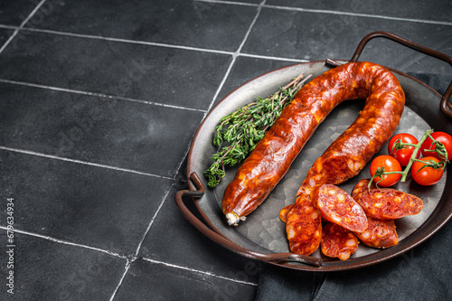 Sliced Chorizo sausage, slices of dry cured pork with herbs and spices. Black background. Top view. Copy space photo