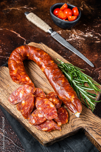 Dry cured Spanish Chorizo sausage, slices of meat with herbs and spices. Dark background. Top view photo