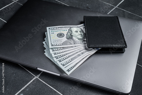 Corporate business desktop with laptop, digital tablet, wallet, money and cup of coffee. Black background. Top view. Copy space