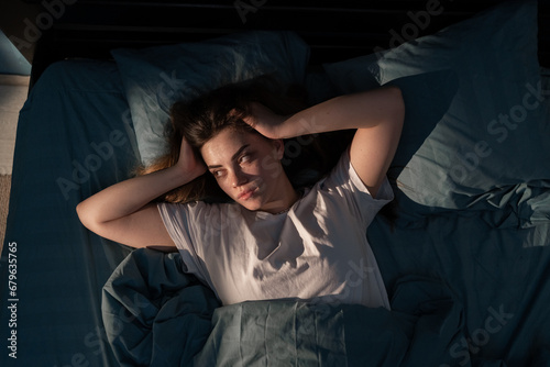 Restless people. Annoyed, Stressed young woman suffering from insomnia, awake in bed at night with headache because of disturbed loud noise, unable sleep.