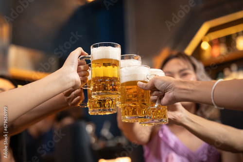 Close-up Group of People Holding Beer and Cheer in Restaurant. They Enjoying with Night Party Together. Party, Lifestyle, Happiness, Cheerful and Celebration Concept. 