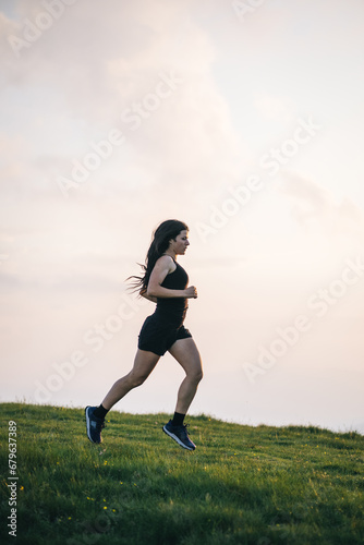 Female trail runner ascending alpine trail in the mountains at sunrise