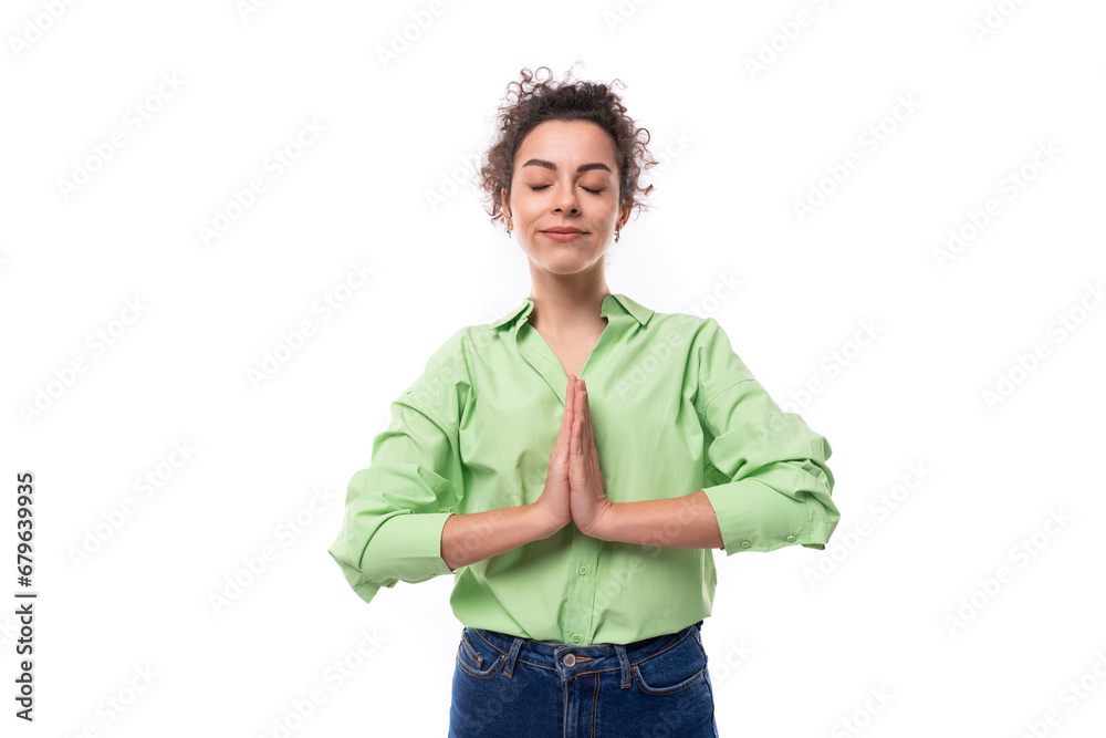young brunette curly slender female model dressed in a light green shirt meditates with folded arms young brunette curly slender female model dressed in a light green shirt meditates with folded arms
