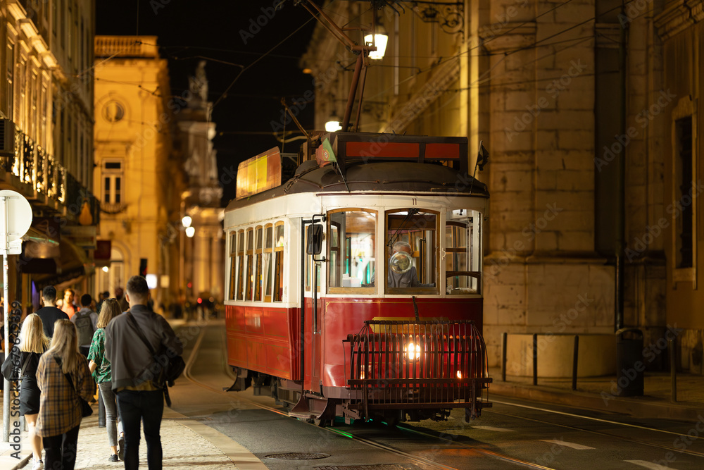Lisbon, Portugal - red trolley car traveling down a street at nigth