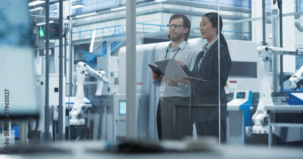 Male Technician and Female Businesswoman Standing in Office, Talking, Using Computers and Monitoring Production at a Modern Automated Electronics Manufacture with AI Robotic Arms Male Technician and Female Businesswoman Standing in Office, Talking, Using Computers and Monitoring Production at a Modern Automated Electronics Manufacture with AI Robotic Arms