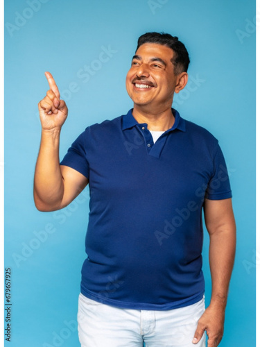 A handsome middle-aged man, isolated on an empty blue background, with a smile, positive and confident expression, pointing his finger to the side, showing an idea, a concept, a success