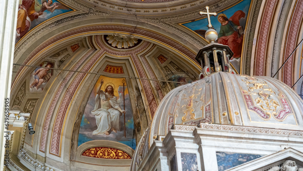 Detail of frescoes and cross above canopy inside catholic cathedral in Italy
