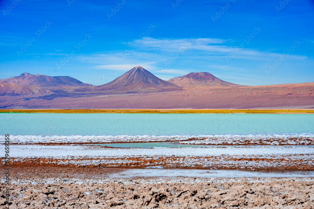 Laguna Tebenquiche, um lago de sal com cores vibrantes azul, verde e amarela ao lado do vulcão Licancabur.  