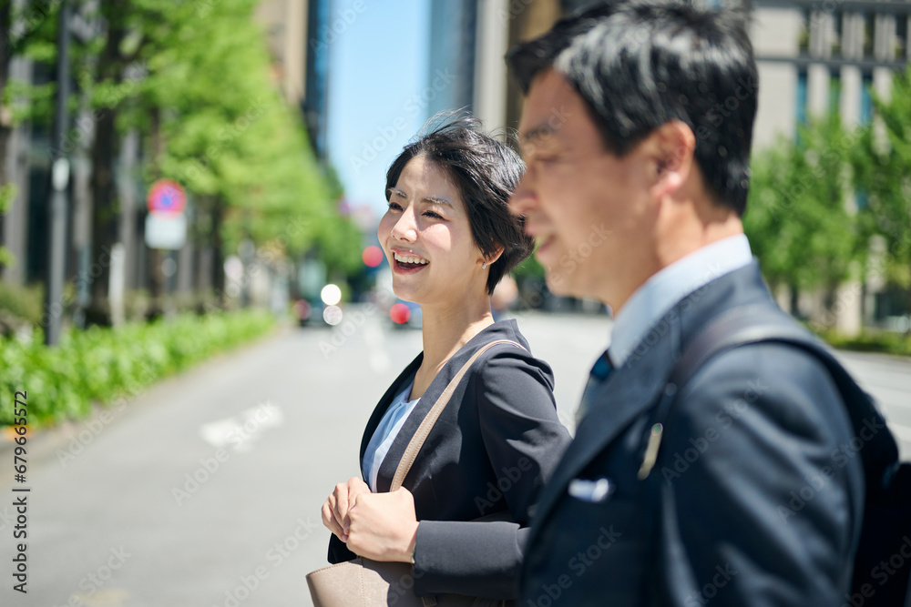 ビジネス街を歩く50代男性会社員と30代女性会社員