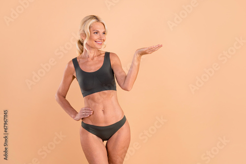 Photo of feel young fresh skin mature woman blonde hair show hold arm empty space proposition undressed isolated on beige color background © deagreez