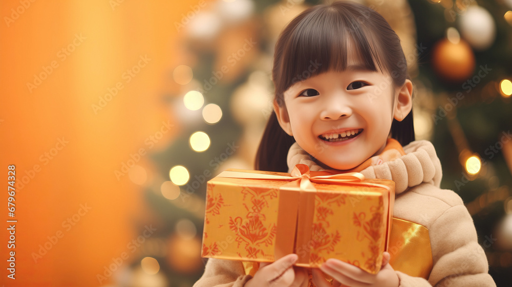 Happy Chinese little girl hugging gift box, Asia China Christmas on background with light bokeh of xmas tree, warm mood banner