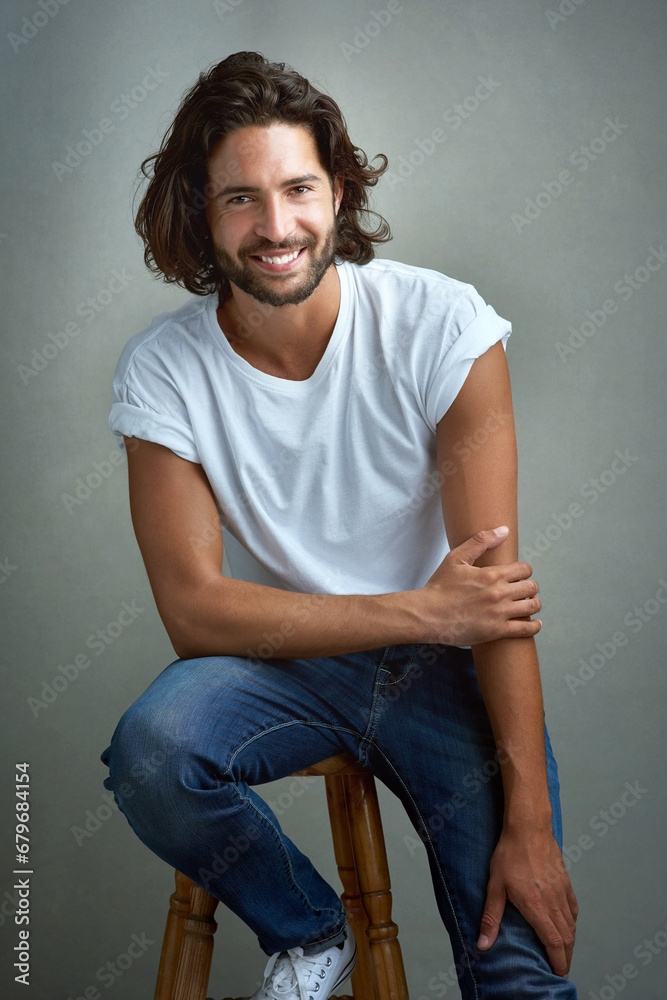 Style, happy and portrait of man in studio on a stool with casual, cool and stylish outfit. Smile, handsome and confident young male model from Mexico with trendy fashion on chair by gray background. Style, happy and portrait of man in studio on a stool with casual, cool and stylish outfit. Smile, handsome and confident young male model from Mexico with trendy fashion on chair by gray background.