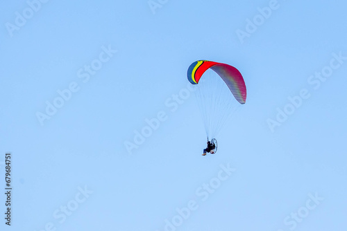 A Powered paragliding also knows as Paramotor flying through the blue sky. Sport. Leisure. Adventure.