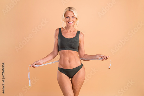Billede på lærred photo of charming retired lady coach measure waist after practice regime isolate