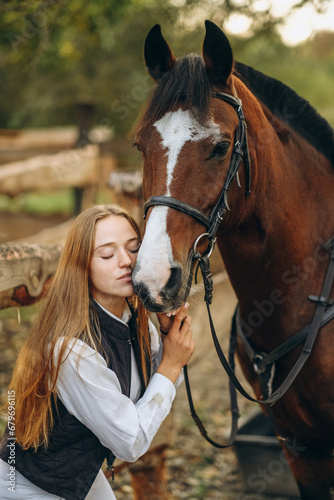 A young female equestrian stands near her horse and prepares for a competition.