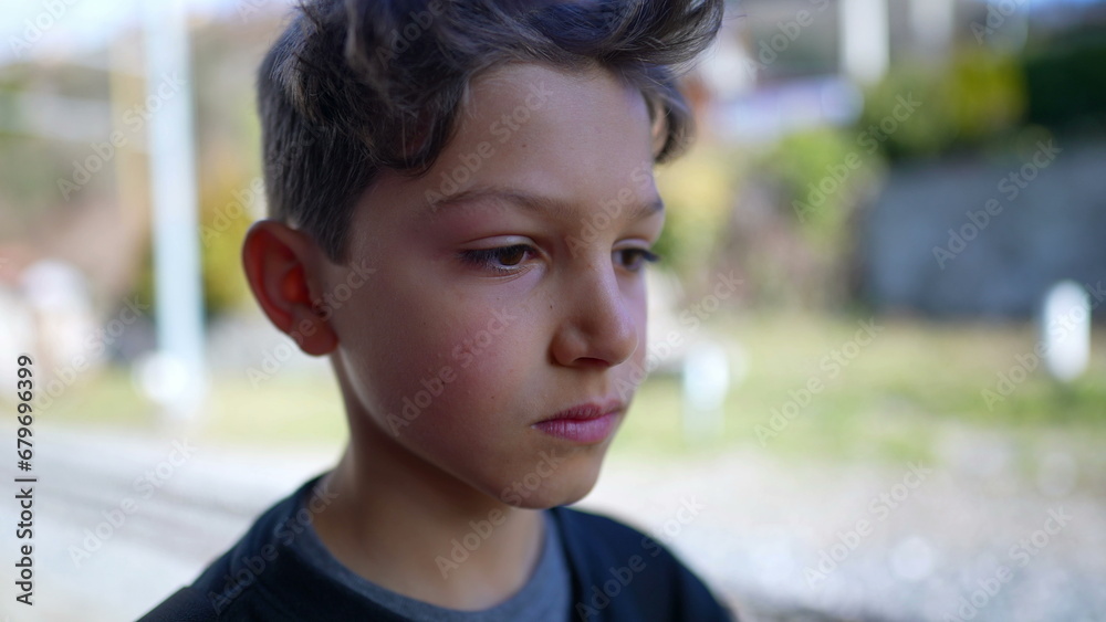 Serious young boy close-up face looking at camera standing outside Serious young boy close-up face looking at camera standing outside