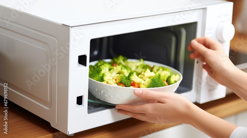 a person holding a bowl of food in a microwave