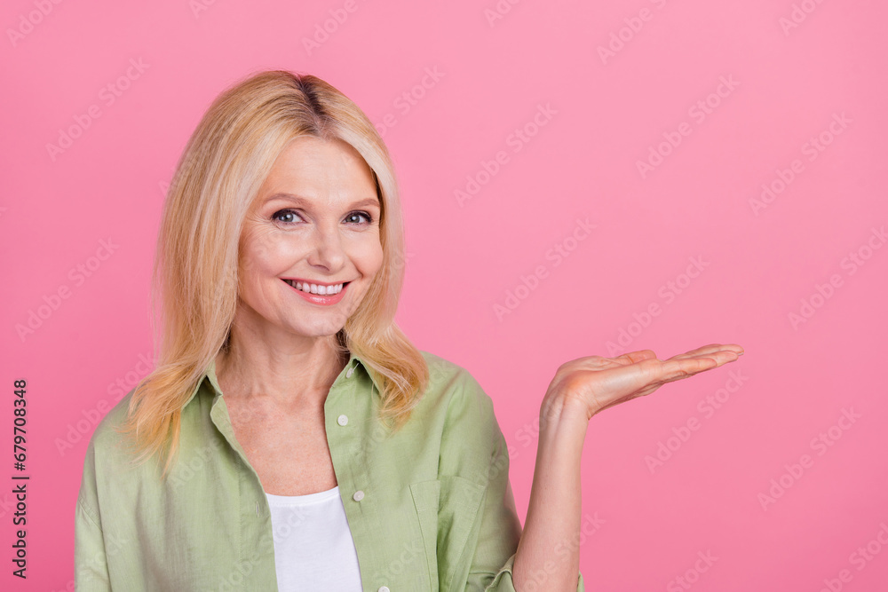 Photo of retired gorgeous woman consultant marketer wear stylish khaki clothes presenting new product isolated on pink color background Photo of retired gorgeous woman consultant marketer wear stylish khaki clothes presenting new product isolated on pink color background