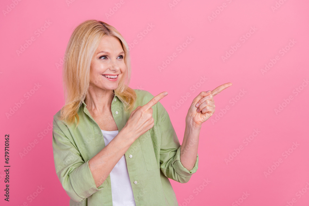Photo of gorgeous woman pensioner wear stylish khaki clothes two arm direct empty space isolated on pink color background Photo of gorgeous woman pensioner wear stylish khaki clothes two arm direct empty space isolated on pink color background