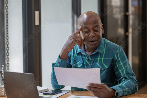 Senior black man in casual clothes holding and focus on document in hands, Verifying report, Consider the project plan as well.