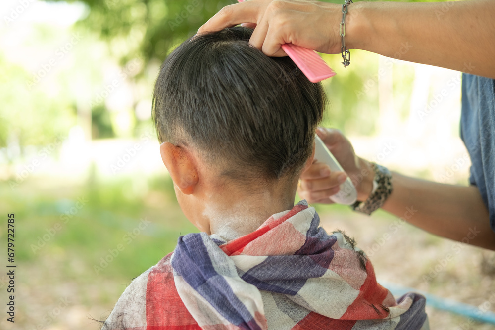 Barber cutting hair of an Asian boy In an open space filled with trees. Barber cutting hair of an Asian boy In an open space filled with trees.