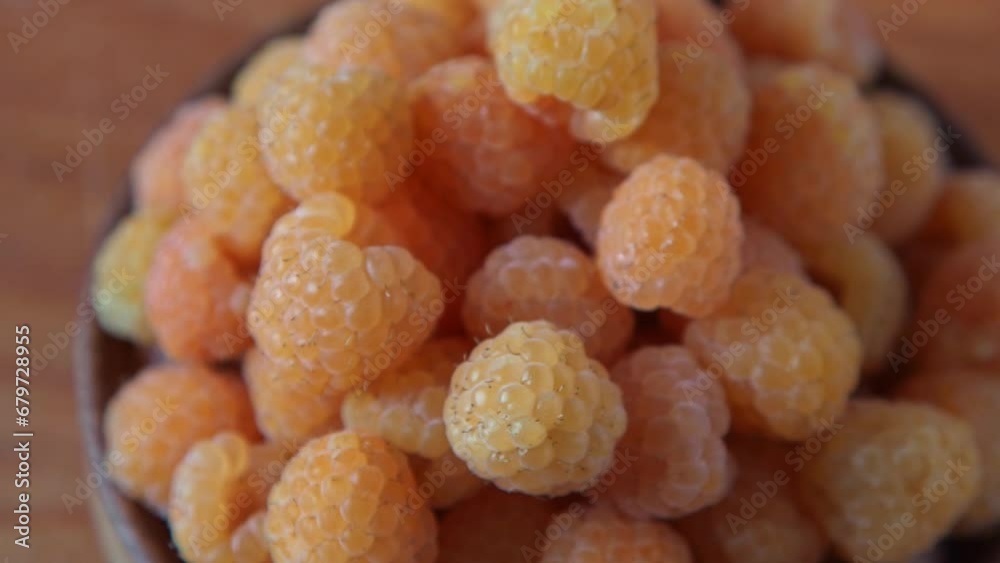 Yellow raspberries in a wooden bowl on the table. Summer berries background. Vitamin food, berry harvest. Healthy nutrition. Yellow raspberries in a wooden bowl on the table. Summer berries background. Vitamin food, berry harvest. Healthy nutrition.