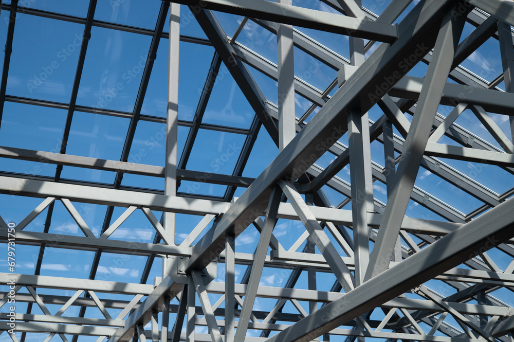 Glass roof against the blue sky. Construction made of steel supports and transparent glass.