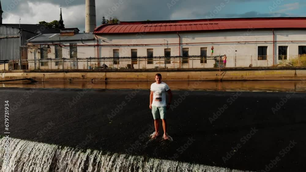 A drone view of a young guy standing on the dam of the Jizera River in the Czech Republic. Dam on the Jizera River in the Czech Republic. Village in Semilsky district of Liberec region A drone view of a young guy standing on the dam of the Jizera River in the Czech Republic. Dam on the Jizera River in the Czech Republic. Village in Semilsky district of Liberec region