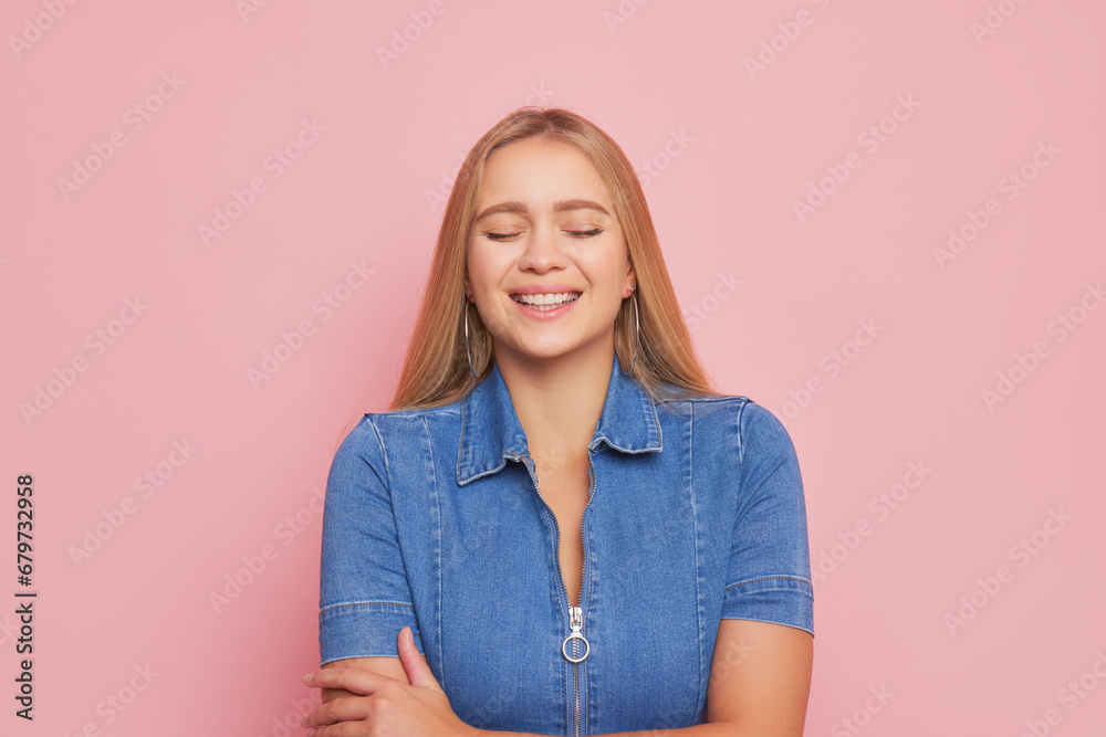 Fototapeta premium Blonde young woman with long hair in glasses dressed in denim shirt posing isolated on pink background, happy life concept, copy space