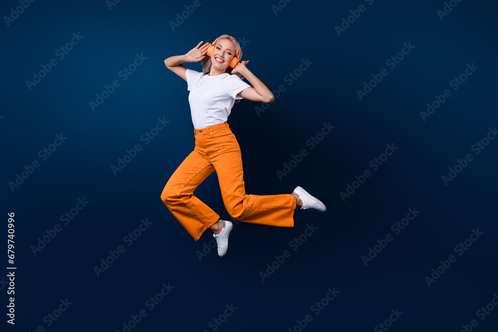 Full length photo of overjoyed cool girl wear trendy clothes jump up rejoice seasonal sale holiday isolated on dark blue color background