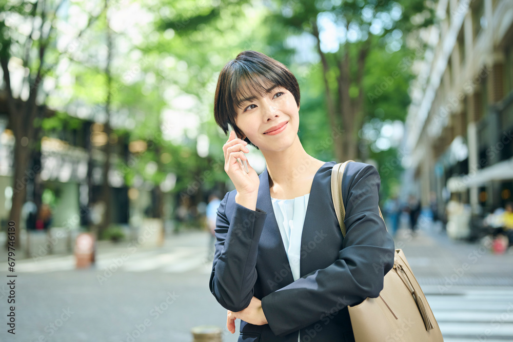 街中で電話をする30代女性会社員,笑顔 街中で電話をする30代女性会社員,笑顔