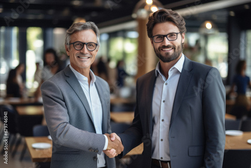 Portrait of two businessmen shaking hands while standing in a coffee shop.