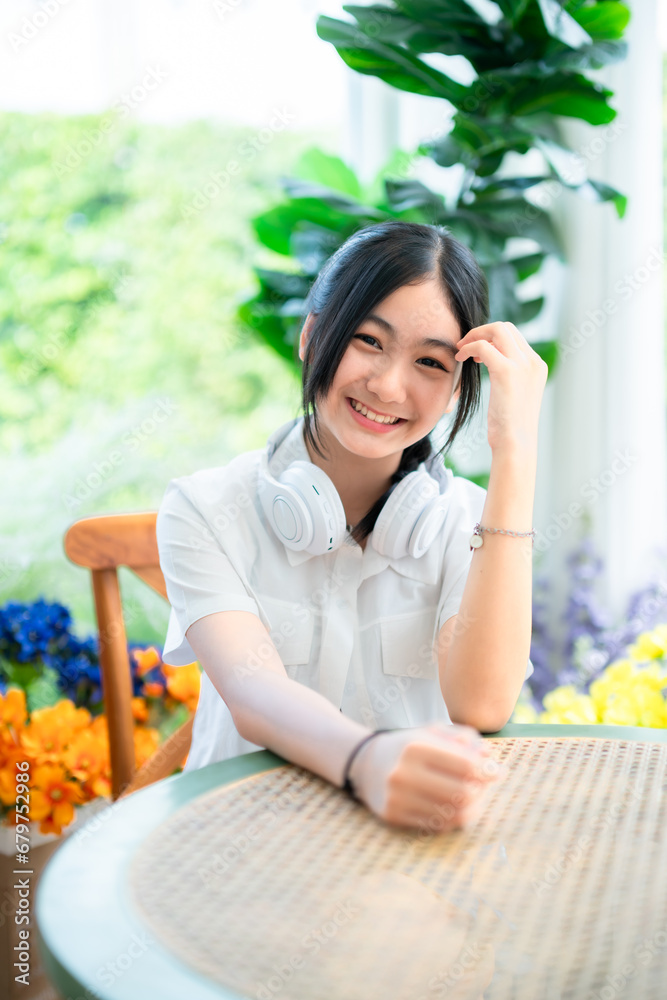 Happy of cute smiles Asian of attractive young Cute little girl wearing white wireless headphones and listening music enjoying favourite audio at the cafe on vacation at a coffee shop. Happy of cute smiles Asian of attractive young Cute little girl wearing white wireless headphones and listening music enjoying favourite audio at the cafe on vacation at a coffee shop.