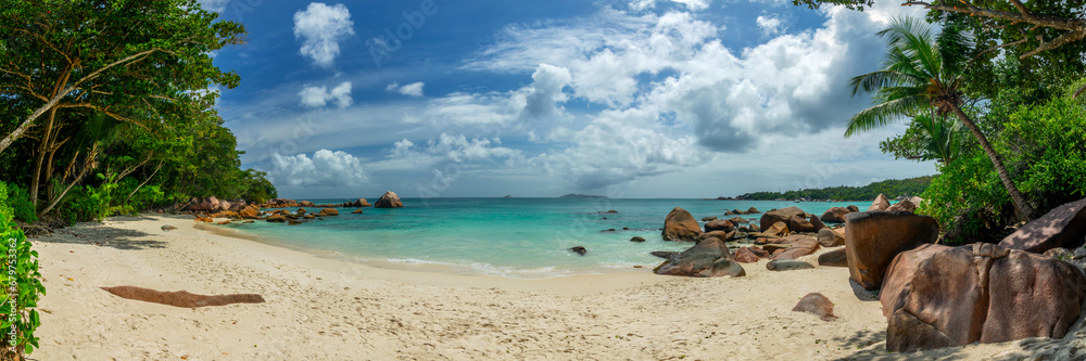 Panorama with palm trees and granite rocks at Anse Lazio, scenic beach in Praslin island, Seychelles web banner