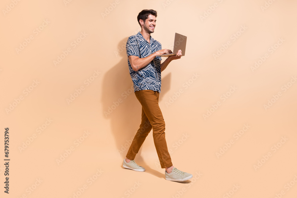 Fototapeta premium Full body length photo of happy young guy professional programming code working remotely using netbook isolated on beige color background