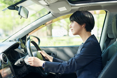 車を運転する30代女性会社員 © One