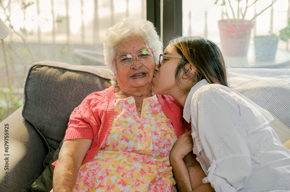 Fototapeta premium Grandmother receives a kiss from her loving granddaughter.