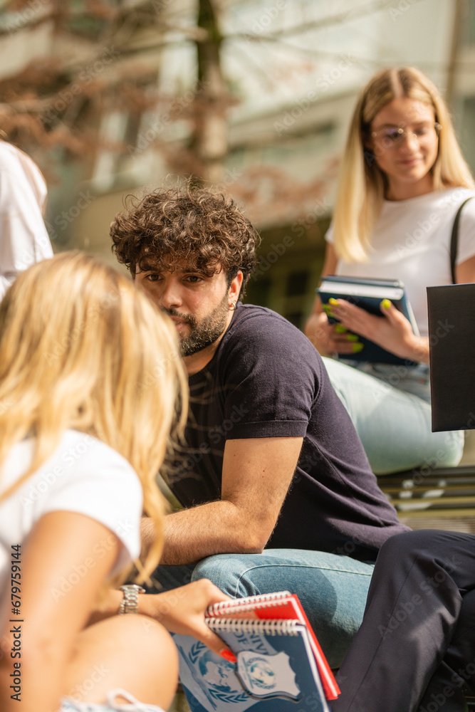 Group of classmates sitting down outside, talking and smiling Group of classmates sitting down outside, talking and smiling