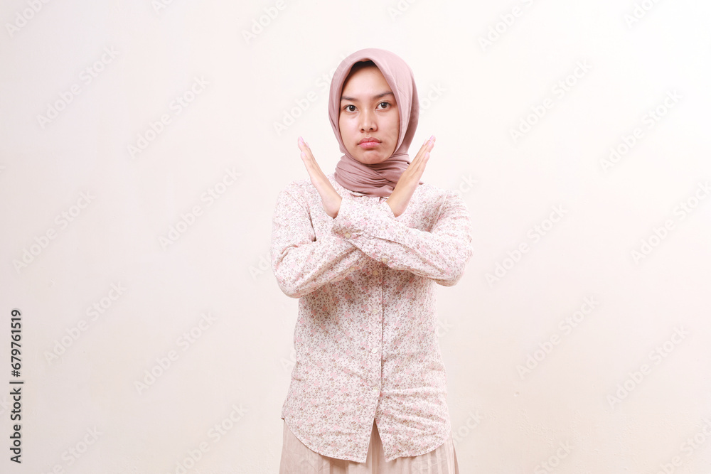 Young asian muslim woman standing while crossing her hand. Definitely no, prohibited access. Showing x sign, stop gesture, warning of end finish Young asian muslim woman standing while crossing her hand. Definitely no, prohibited access. Showing x sign, stop gesture, warning of end finish