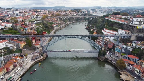 Cinematic aerial view of Dom Luis I Bridge. Situated in Portugal between the cities of Porto and Vila Nova de Gaia. Train passing. Drone going backwards photo