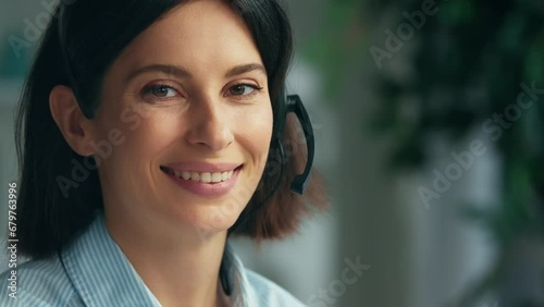 Young woman working in a call center. Happy smiling call center operator answering phone calls wearing headphones. Call center and helpful customer service. Working at customer care. Close up