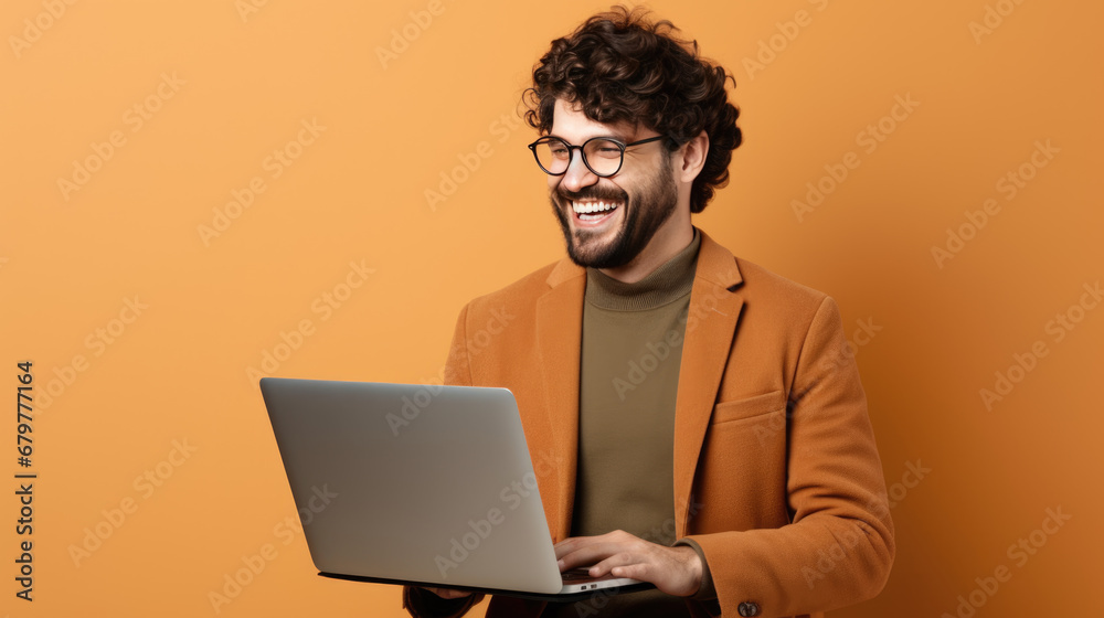 Happy young man working on a laptop against beige background Happy young man working on a laptop against beige background